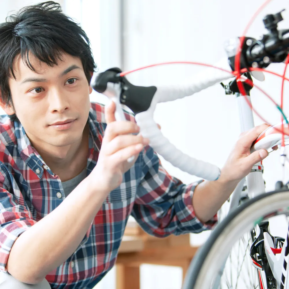 男性が室内で自転車の点検や調整をしている様子